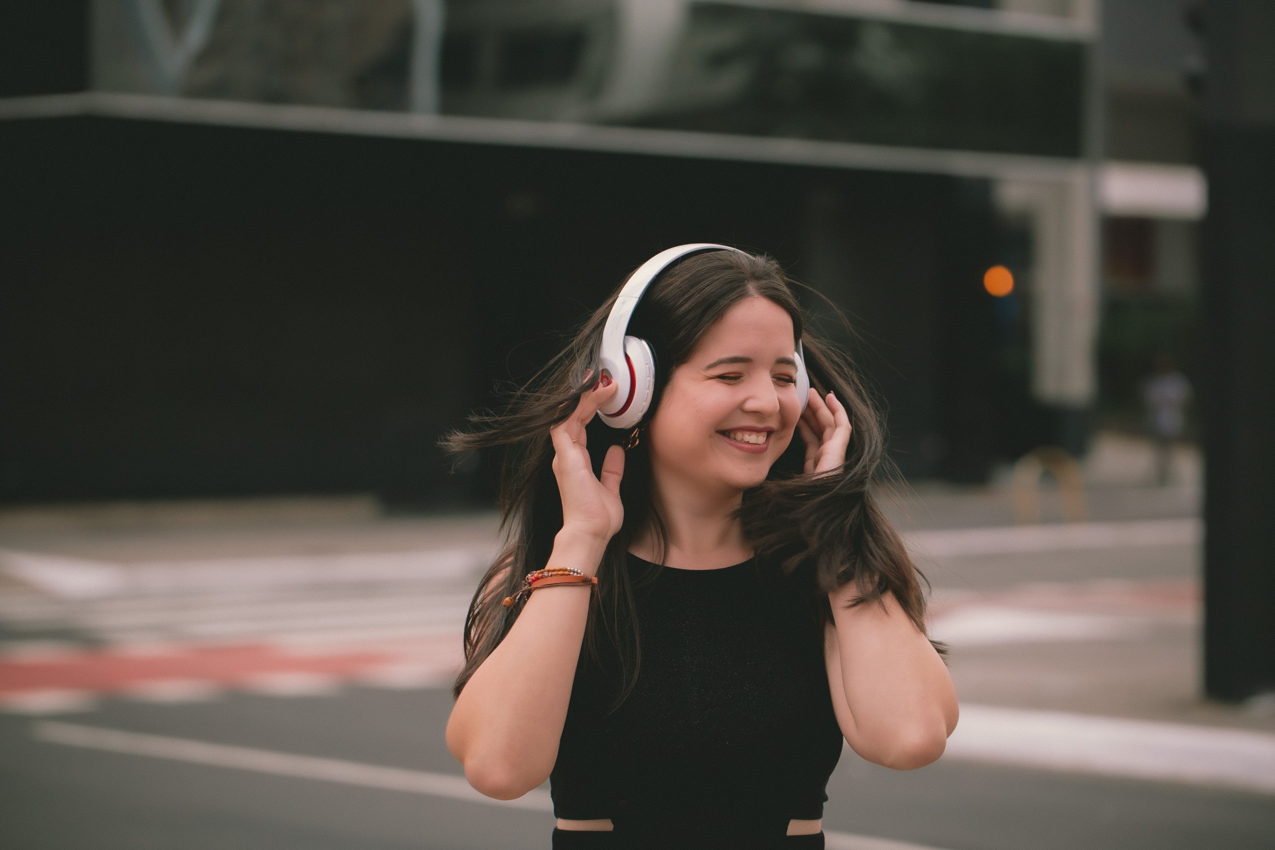 Femme souriante écoutant musique casque bluetooth urbain