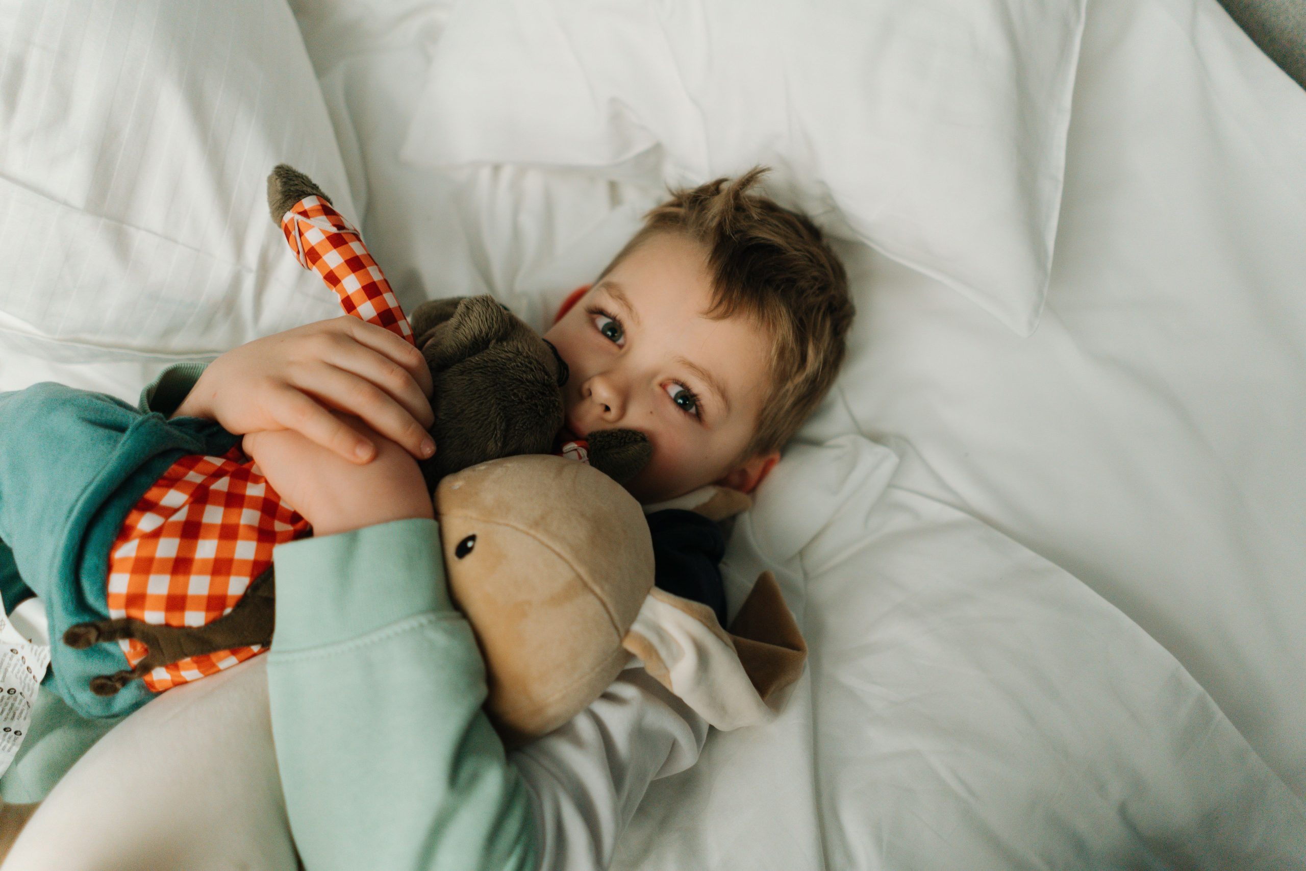 Jeune enfant câline ses peluches sur son lit